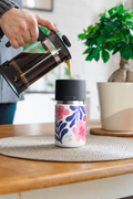 IRISgo cup sip 350ml Boho Coral Design auf dem Tisch beim Kaffee einschenken – Swiss Made Thermobecher für zuhause und unterwegs