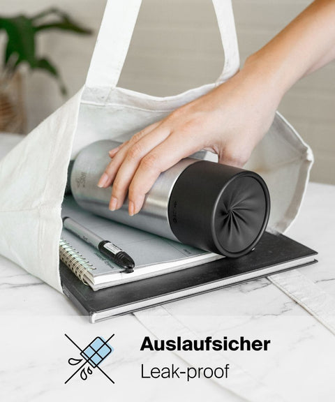 Auslaufsicherer IRISgo® cup flow 500ml Thermobecher in roasted black liegt in einer Tasche auf Notizbüchern