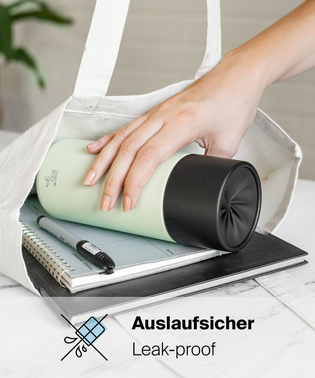 IRISgo® cup Thermobecher liegt auslaufsicher in der Tasche auf Notizbüchern