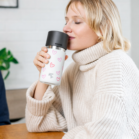 Frau trinkt aus dem IRISgo Thermobecher mit Herz-Design – stilvoller Becher für Kaffee oder Tee